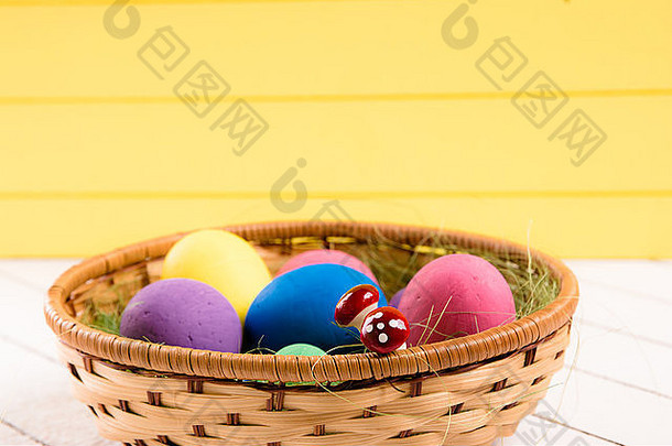 <strong>木</strong>制背景上篮子里的彩色复活节彩蛋。无暴力侵害动物的环保材料