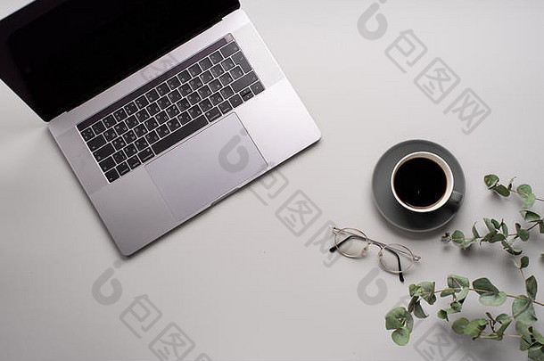 平板电脑，桉树和一杯咖啡的灰色背景。工作空间概念。拷贝空间