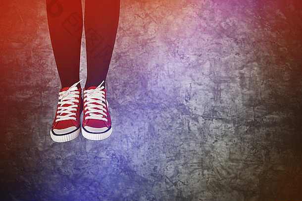 粗心的年轻女子欢蹦乱跳，穿着红色运动鞋，背景是垃圾