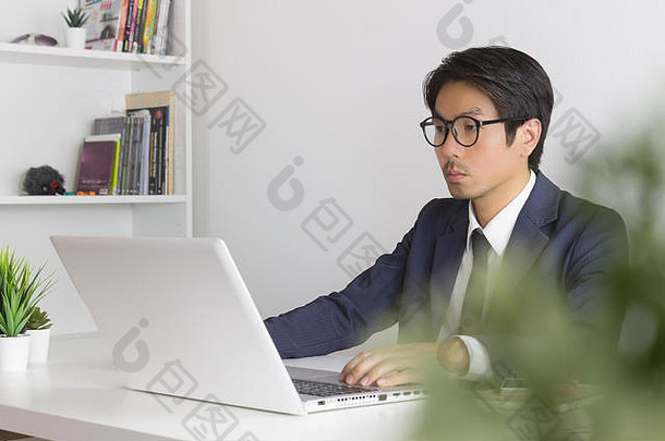 亚洲金融顾问或亚洲咨询商人在笔记本电脑前认真工作。亚洲金融顾问或亚洲咨询商人
