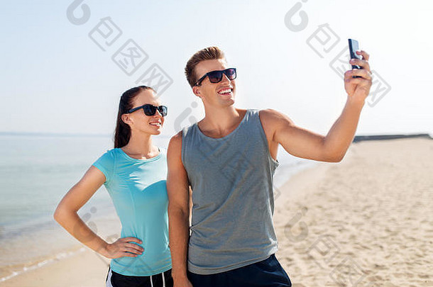 一对情侣在海滩上用智能手机自拍
