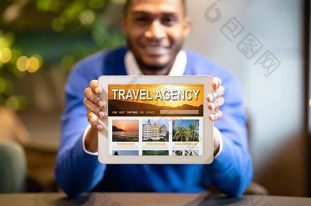 黑人手持数字平板电脑，在屏幕上打开旅行社网站
