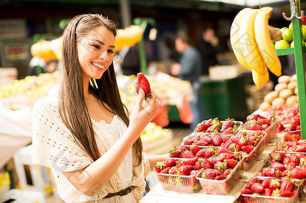 在市场上寻找和购买新鲜水果的年轻女子