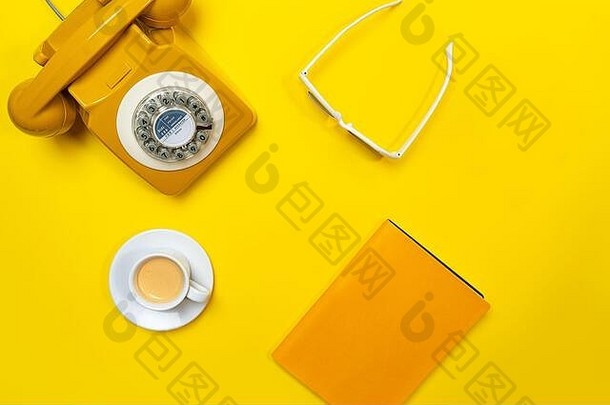 黄色布局，复古旋转电话，咖啡杯，太阳镜和笔记本。平面布局、俯视图、空间。