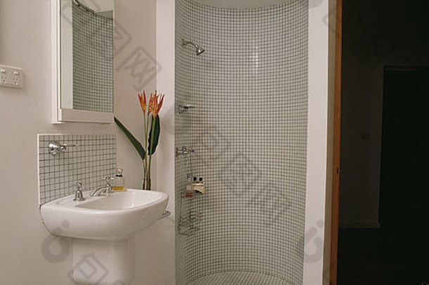 现代白色浴室中的马赛克瓷砖步入式圆形淋浴柜，带壁挂式洗脸盆