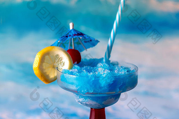 五颜六色的蓝色鸡尾酒，柠檬和樱桃色装饰，蓝色饮料伞