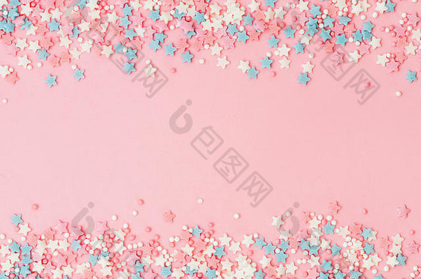 彩色粉彩的节日边框洒在粉色背景上，中间有空间。糖洒点和星星，装饰蛋糕和面包房。俯视图或平面图