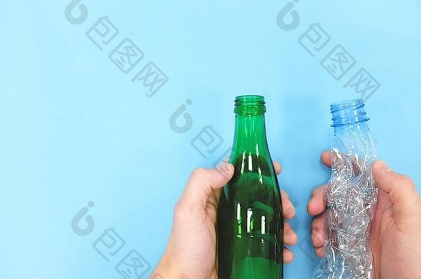 手拿着蓝色背景的空塑料瓶和玻璃瓶。绿色理念。玻璃和塑料容器。