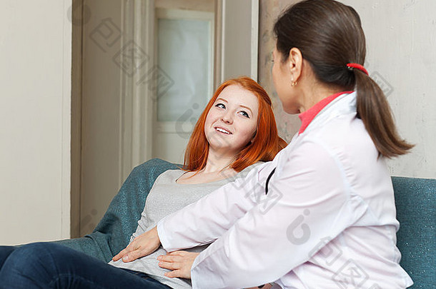 成熟的医生在室内触摸青少年的腹部。关注患者