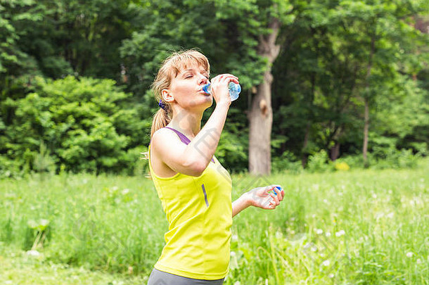 健身妇女从瓶子里喝水。
