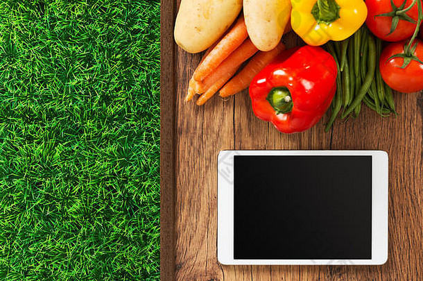 触摸屏数字平板电脑，木桌上的新鲜蔬菜和草，食品和园艺应用程序概念