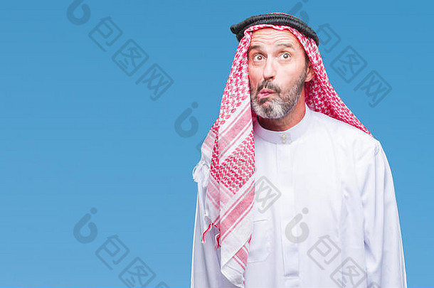 高级阿拉伯男子在孤立的背景下穿着keffiyeh，用嘴唇<strong>做鱼</strong>脸，疯狂而滑稽的手势。滑稽的表情。