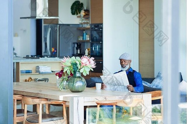 男人在餐桌上看报纸喝咖啡