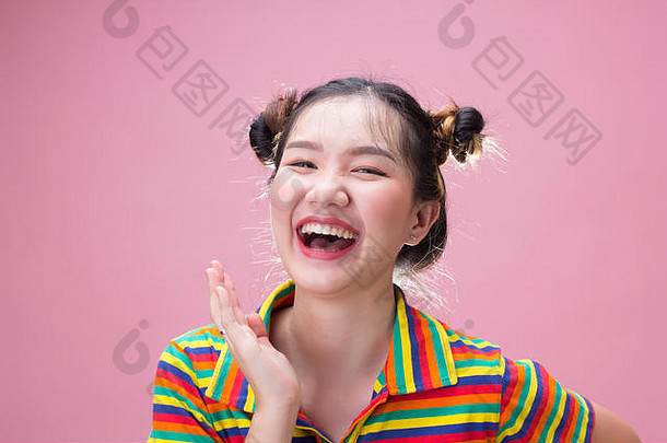 年轻漂亮的亚洲女人在粉红色背景下快乐地笑着