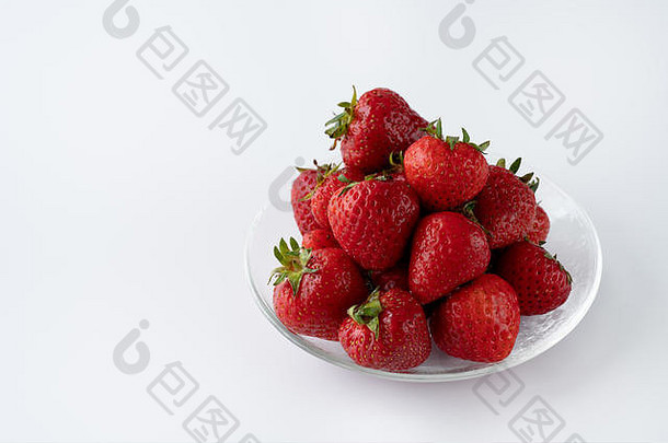 在玻璃碗中新鲜采摘的有机草莓。白色背景、水、隔离、高分辨率