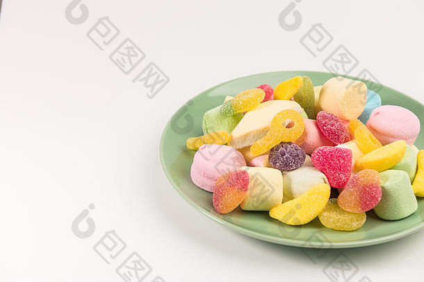 盘子里有白色背景上分离出来的糖果。软糖和棉花糖。