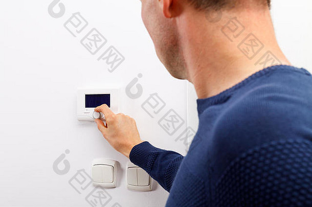 男人们在客厅墙壁上的中央暖气控制面板上调节温度。