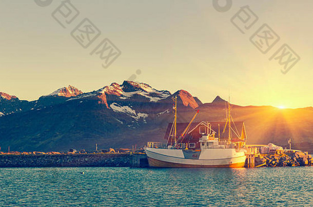挪威北部，罗弗敦岛，兰贝格，挪威，午夜阳光下港口里的渔船——背景是山