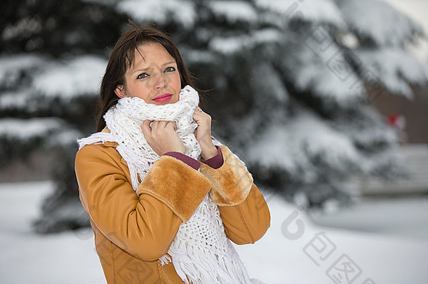 圣诞节，一个女孩兴高采烈地站在白雪覆盖的云杉旁