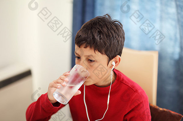 小男孩一边看电脑一边喝着一杯水——视野很浅