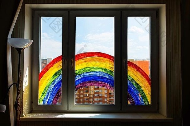 儿童绘画彩虹在2019冠状病毒疾病在家检疫。靠近窗户的女孩。在家社交媒体上开展预防冠状病毒的活动，让我们共同努力