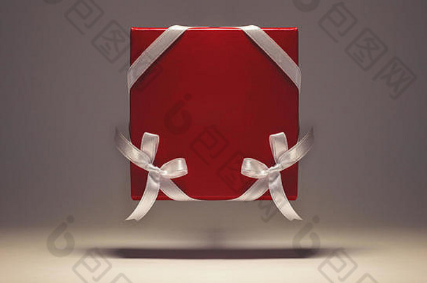 在灰色背景上用白色丝带装饰的红色盒子。