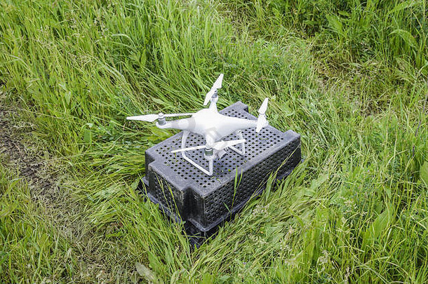 草地上一个塑料盒子上的四翼机。准备起飞。
