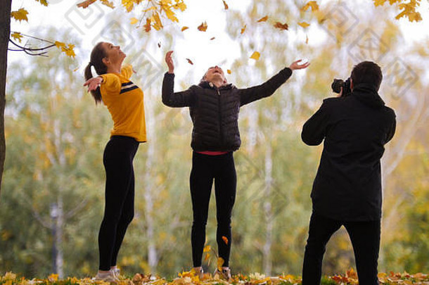 杂技女孩在摄影师面前摆姿势，向空中扔黄叶。