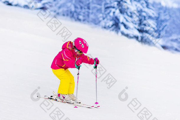 孩子们在山上滑雪。带安全帽、护目镜和杆子的活泼幼儿。幼儿滑雪比赛。