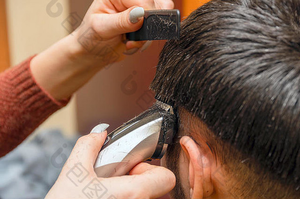女理发师用电动剪刀修剪男人的头发