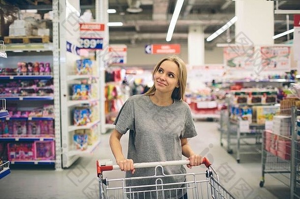 超市里好奇的女人。在商场购物的小女孩在想买什么