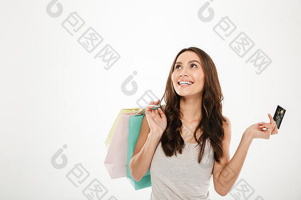 在白色墙壁复印空间上，一个快乐的女人手里拿着很多东西，用购物