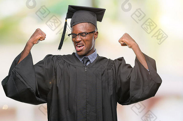 年轻<strong>毕业</strong>的非裔美国男子在与世隔绝的背景下<strong>展</strong>示手臂肌肉，自豪地微笑。健身理念。