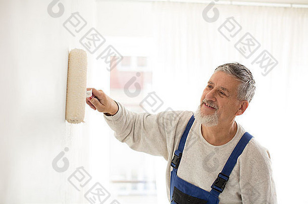 老人用油漆辊在墙上刷漆，微笑着，享受着工作