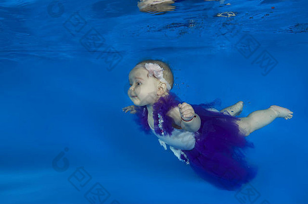 穿着芭蕾舞服的小女孩在游泳池里漂浮在水下