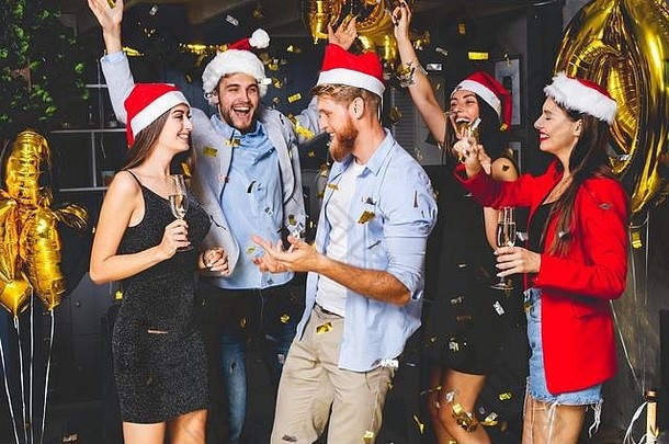 庆祝一年集团美丽的年轻的人圣诞老人帽子扔色彩斑斓的五彩纸屑快乐