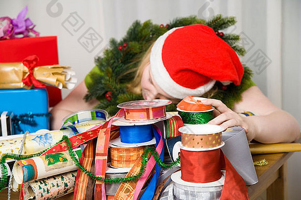 穿着圣诞老人服装的女人睡在礼物包装材料上