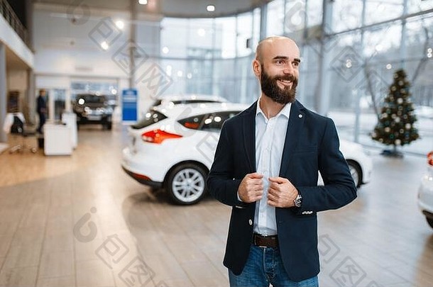 微笑的男人在汽车经销店摆姿势