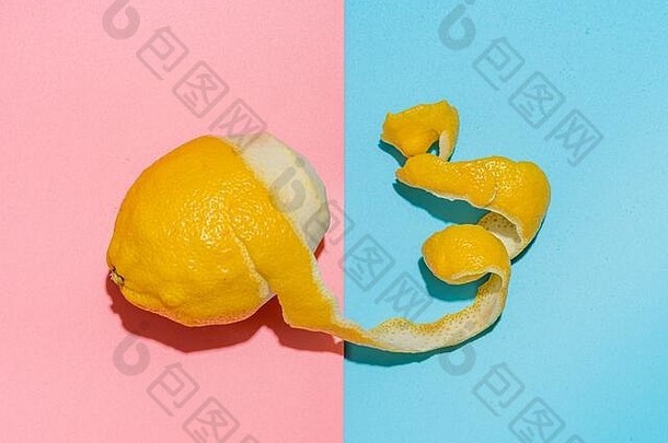 在蓝色和粉色的极简背景上，柠檬有着螺旋状的去皮热情。柠檬和果皮在强光下。俯视图或平面图。夏季极简创意概念与布局