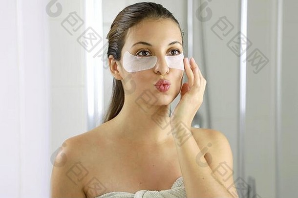 迷人的女人戴着眼罩，在浴室的镜子里看着自己，亲吻自己。皮肤护理女孩触摸法布里贴片
