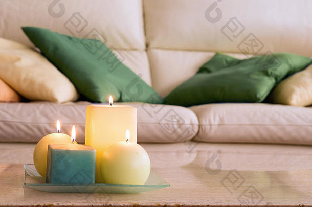 在大理石桌子上点燃蜡烛，背景是一张带枕头的沙发，这