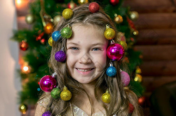 美丽的小女孩在头发上编织圣诞树装饰品。