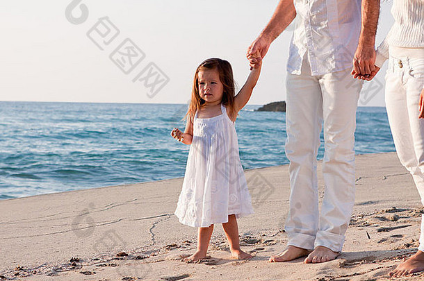 夏日生活方式中带着女儿在海滩上的快乐年轻家庭