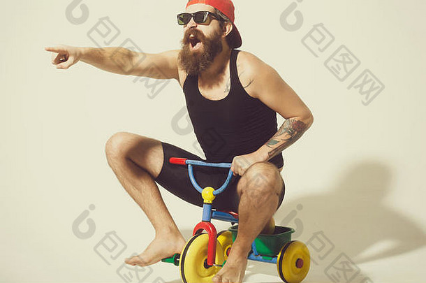戴着墨镜，戴着帽子，戴着彩色自行车玩具，满脸胡须，大喊大叫的男人