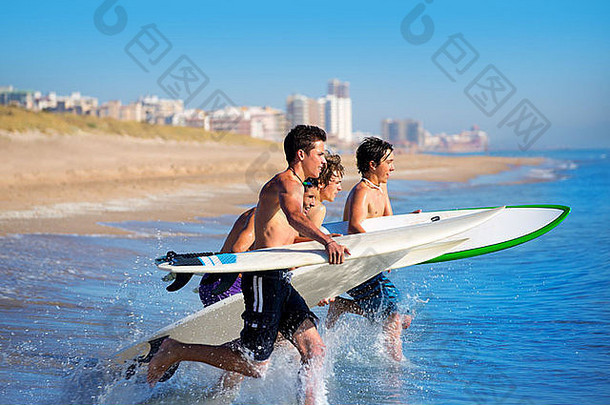 西班牙El Perello Cullera海滩，青少年冲浪者在冲浪板上冲浪、跑步、跳跃