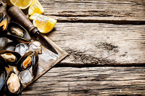 在木板上放柠檬和冰的蛤蜊。在木制背景上。文本的可用空间。