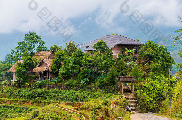 在越南北部美丽的萨帕村外的水稻梯田上，房屋和房屋被群山环绕