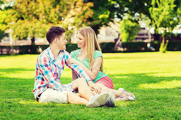 微笑的夫妇坐<strong>在公园</strong>的草地上