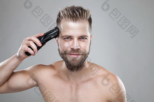 一个留着胡子的英俊男子用剪子剪自己的头发