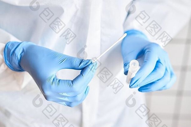 医生手持拭子试管进行2019 nCoV分析。冠状病毒试验。蓝色医用手套和2019冠状病毒疾病保护面罩